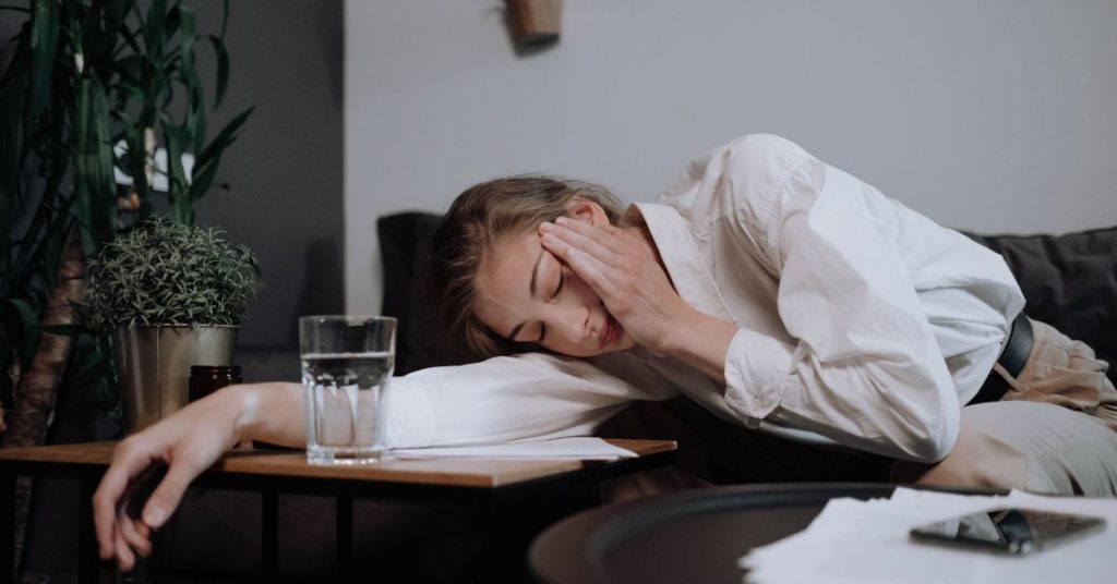 A woman dressed in office attire rests on her arm at a desk, she looks very tired and stressed, Ways to Stop Sugar Craving