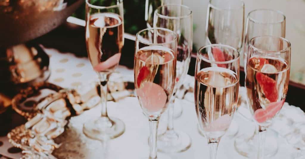 Several flutes of champagne are lined up on a serving tray