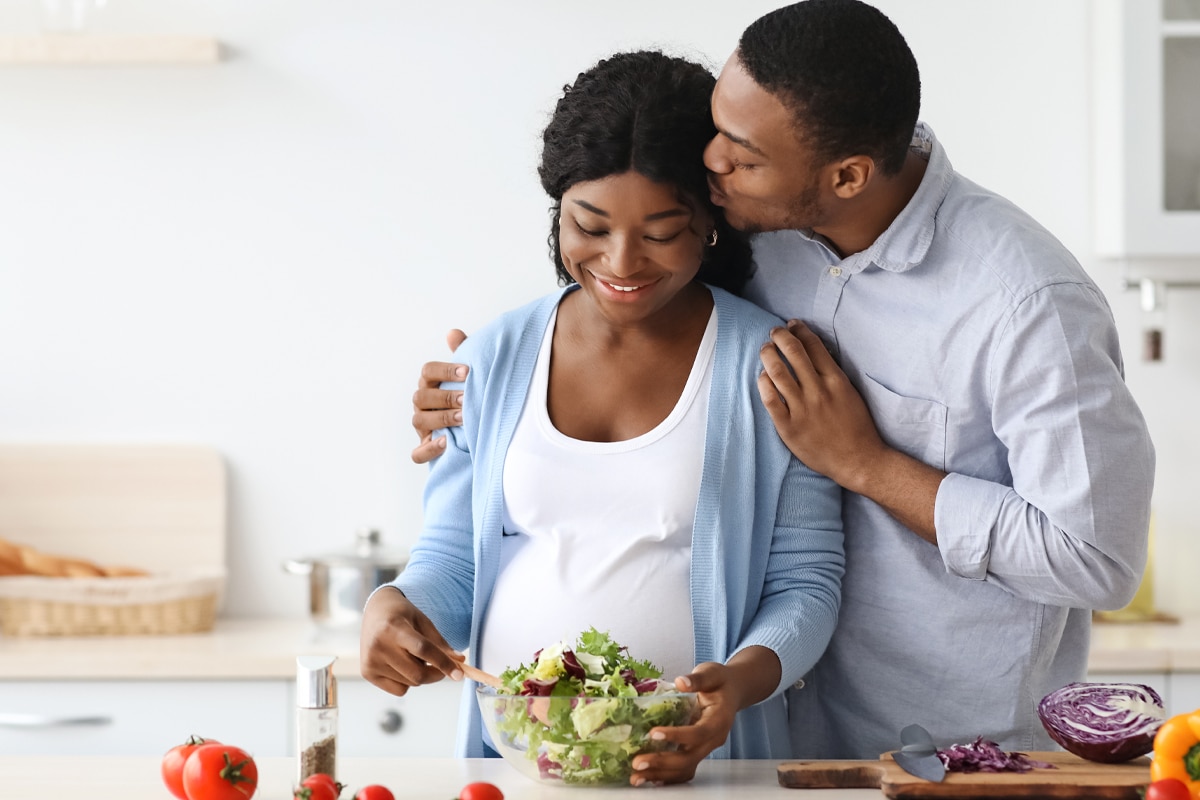 pregnant woman and husband in kitchen making a high-fiber meal to prevent constipation during pregancy