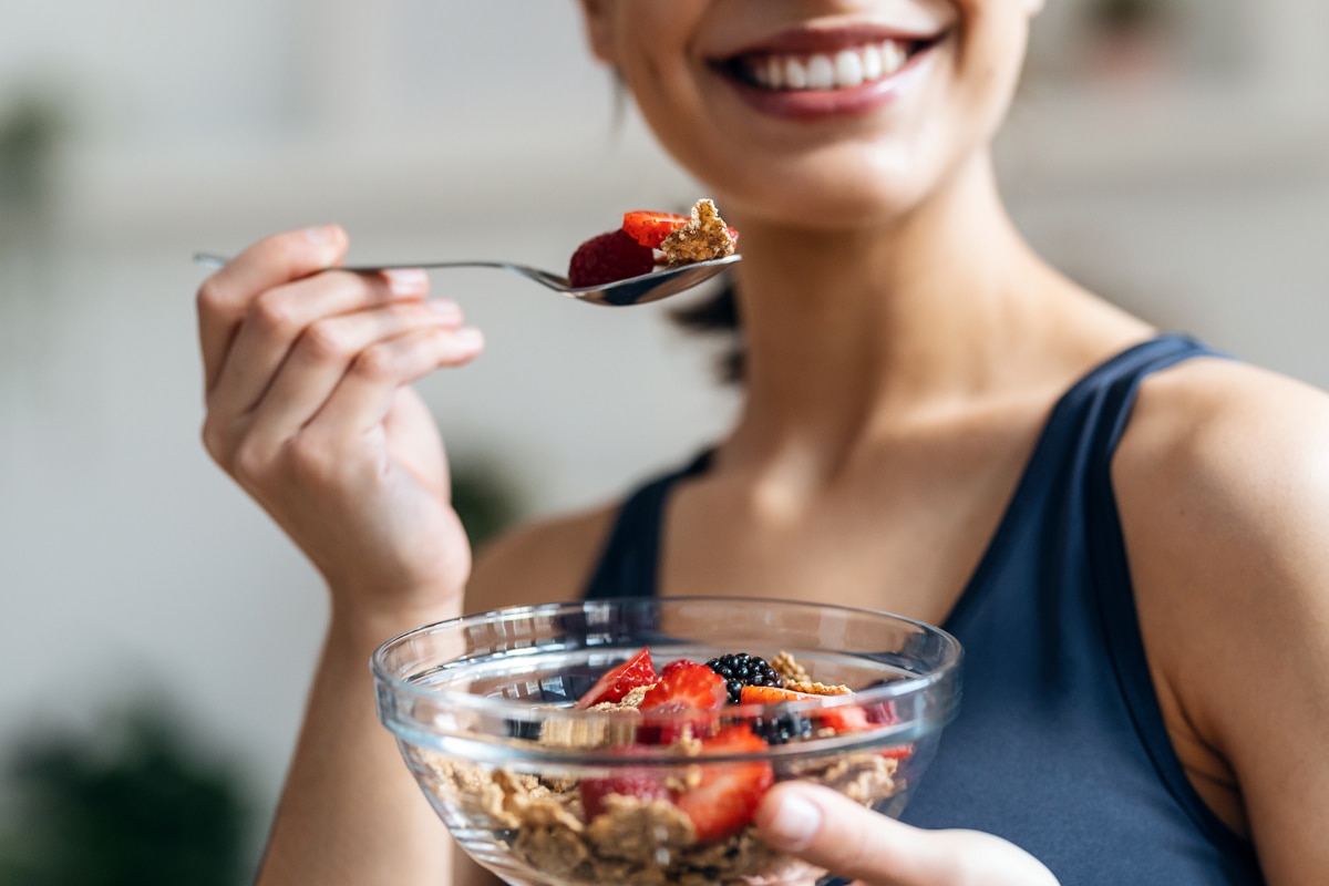woman eating a high fiber breakfast with beries and oats