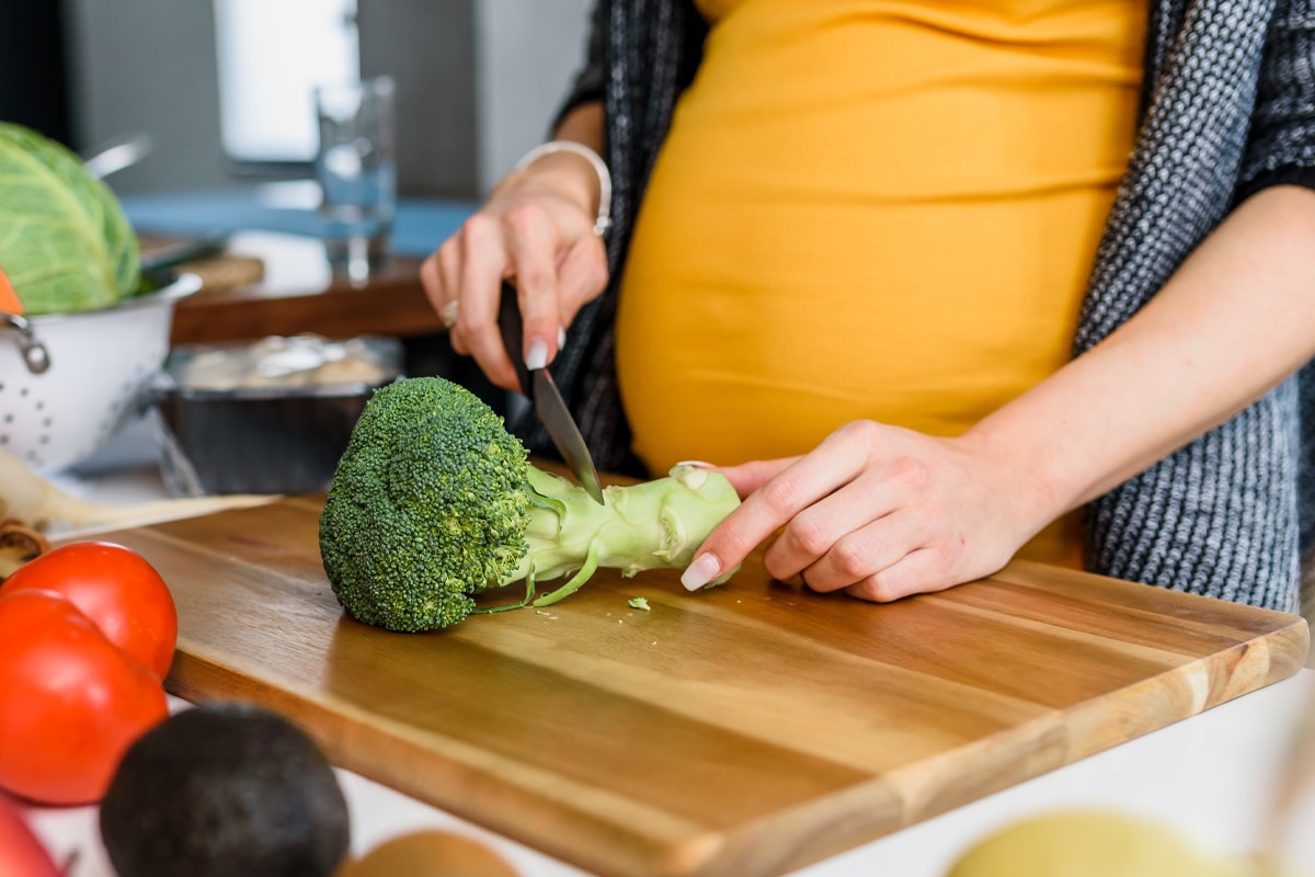 mindful eating during pregnancy - pregnant woman cutting brocolli meal prep
