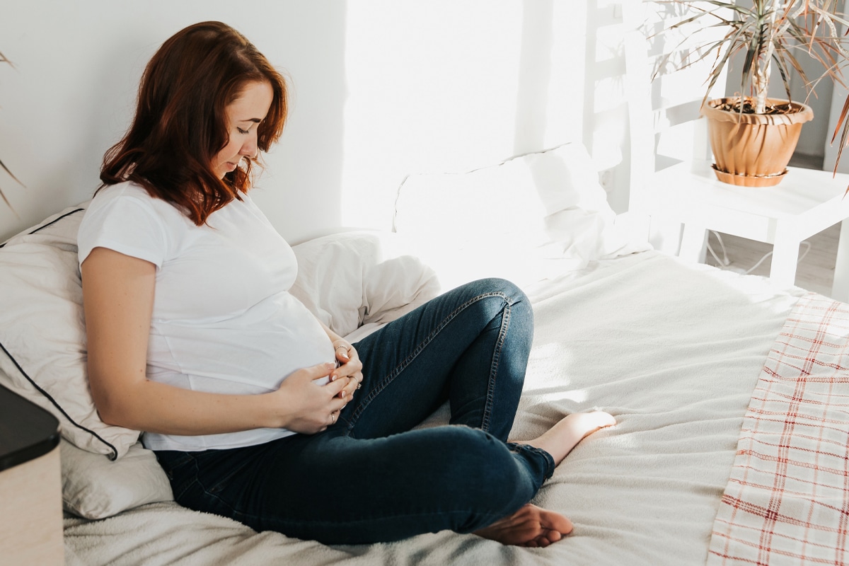 woman with gestational diabetes sitting on bed holding pregnant belly