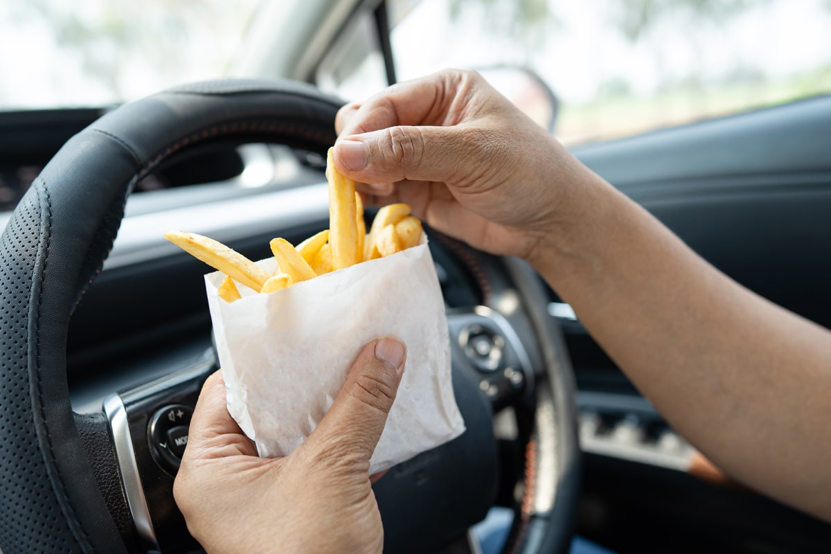 eating out of habit - man eating fries from the drive through in his car