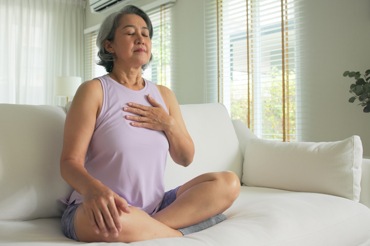 mind body feelings check for triggered eating - woman on couch breathing deeply with eyes closed